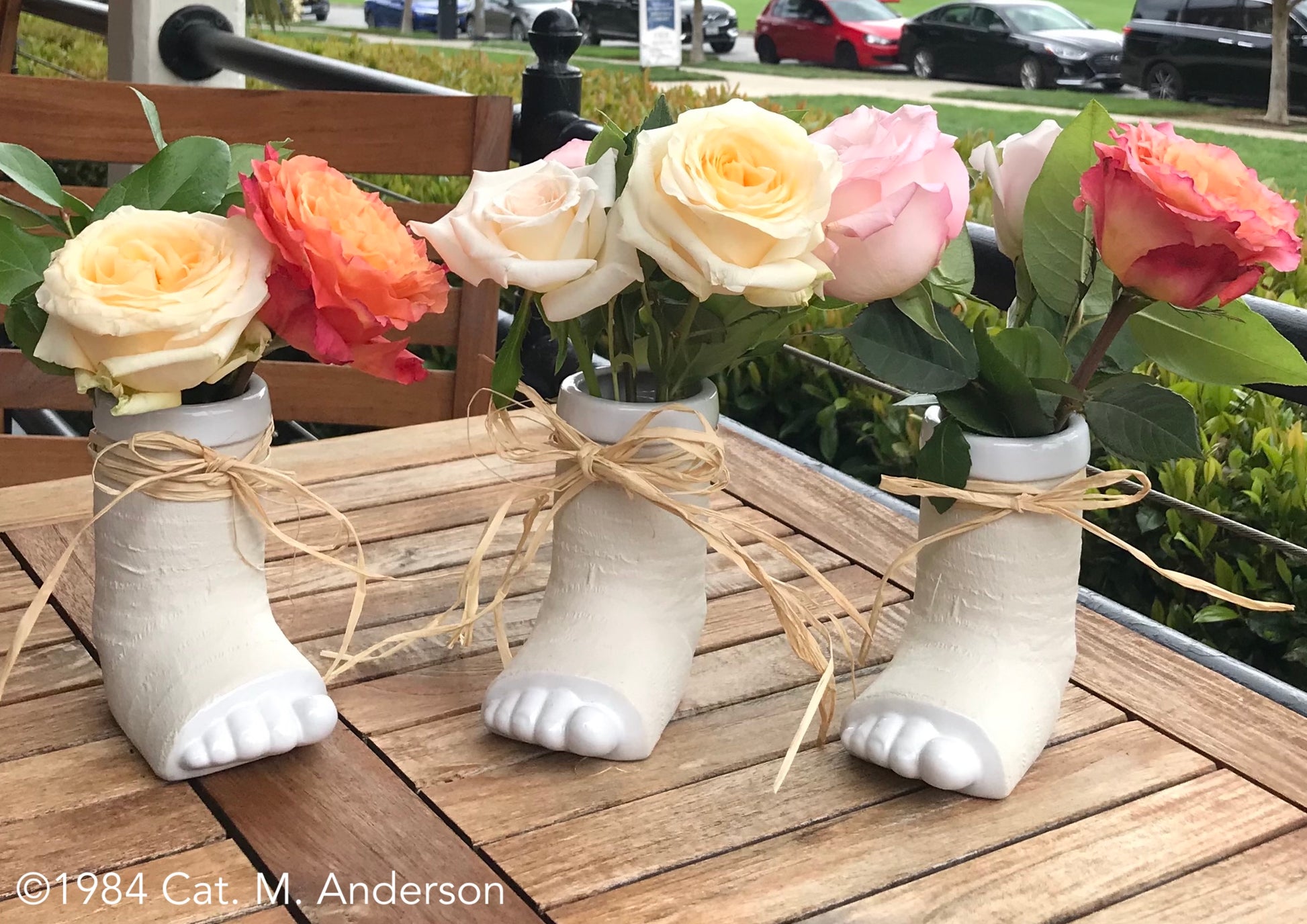 Three break a leg mugs as vases with roses and ribbon, centerpiece on table at a cafe